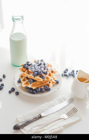 Köstliches Frühstück mit Waffeln mit Blaubeeren und Milch und Honig in Untertasse Stockfoto