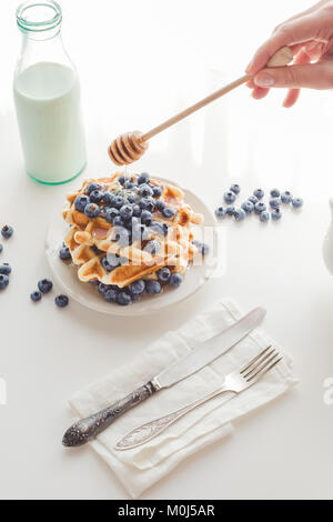 7/8 Schuß von Frau gießen Honig auf leckere Waffeln gestapelt Stockfoto