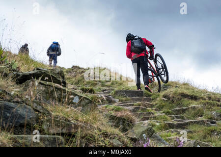 Wanderer und Radfahrer, die ein Fahrrad auf einem steilen Hügel. Jacob's Ladder, Derbyshire, Peak District National Park, England, Großbritannien Stockfoto