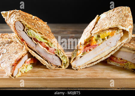 Shawarma chicken Roll in ein Fladenbrot mit frischem Gemüse und Sauce auf Holz- Hintergrund. Selektiver Fokus Stockfoto