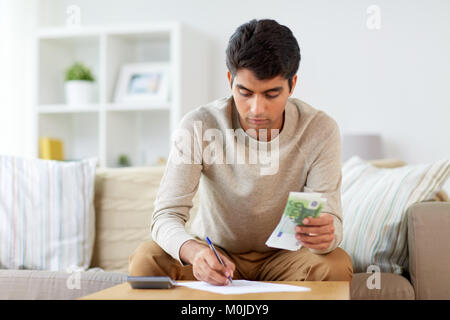 Mann mit Geld und Rechner befüllen Papiere Stockfoto