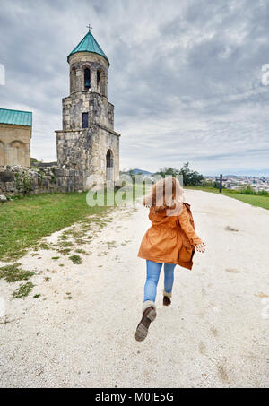 Frau zu laufen, um die Kapelle Turm von bagrati Kirche bei bedecktem Himmel in Kutaissi, Georgien Stockfoto
