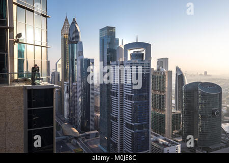 Anzeigen eines Fotografen in Dubai International Financial District bei Sonnenaufgang von einem Aussichtspunkt auf dem Dach gesehen. Dubai, VAE. Stockfoto