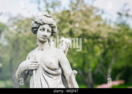 Alte Marmorstatue von Diana, die Göttin der Jagd, des Mondes und der Natur, Park. Sonniger Frühlingstag, weibliche Jäger mit Pfeil und Bogen. Stockfoto