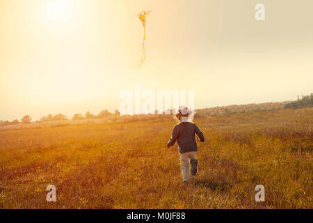 Kleines Mädchen flying a Kite im Bereich vorsätzliche Steigung der Horizont die Dynamik der Foto zu geben Stockfoto