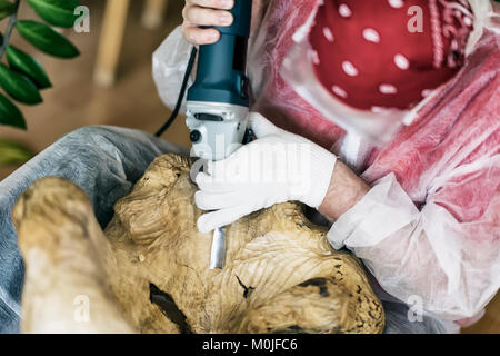 Holzschnitzer mit Brille Schnitzerei aus natürlichen Edelsteinen Holz, Kunst Objekt für die Dekoration von Haus. Hände mit Tools close-up. Konzept der handgefertigten, Professionalität, Hobby Stockfoto