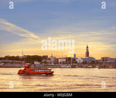 HAMBURG, DEUTSCHLAND - 12. AUGUST 2015: Boot mit Touristen geht auf der Elbe in Hamburg auf einem Sonnenuntergang Stockfoto