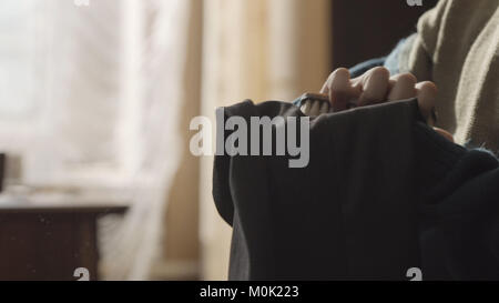 Frau mit einem fusselfreien Pinsel Schmutz von ihrer Kleidung zu entfernen. Frau putzen sie Hosen mit einer Bürste. Woman's Hand mit Bürste zum Reinigen der Kleidung Stockfoto