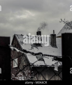 Kalten Wintertag, Haus mit Rauch aus der Schornstein mit Zaun gerahmt Stockfoto