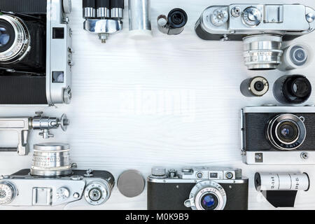 Altes Foto Kameras, Filmrollen, Objektiv und Stativ auf weißem Holz- Hintergrund. frame Design. Flache Ansicht. Stockfoto