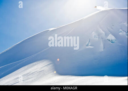 Eine professionelle, Freeriden Snowboarder in der Luft auf einem schneebedeckten Hang vor blauem Himmel, British Columbia, Kanada Stockfoto