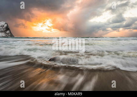 Blur von der Tide Abwasch auf dem sandigen Ufer entlang der Küste und eine goldene Sonne staircase Gewitterwolken, Nordland, Norwegen Stockfoto