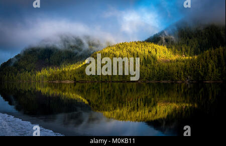 Landschaft der Küstenstreifen mit Wald und ruhigen Ozean spiegelt die Bäume und Wolken; Hartley Bay, British Columbia, Kanada Stockfoto