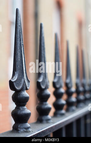 Perspektive der vertikalen Ansicht aus schwarz lackiertem Eisen Zaun spikes vor einer Mauer Stockfoto
