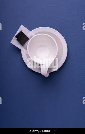 Leere Porzellan weiße Tasse mit einem Teebeutel Becher auf dunkelblauem Hintergrund. Studio shot Top View Stockfoto