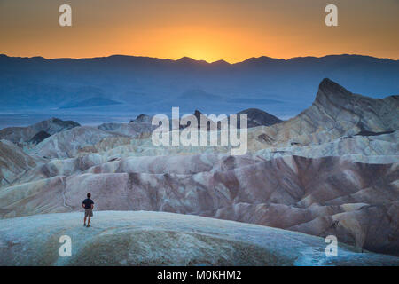 Wanderer am berühmten Zabriskie Point Aussichtspunkt in wunderschönen goldenen Abendlicht bei Sonnenuntergang im Sommer, Death Valley National Park, Kalifornien, USA Stockfoto