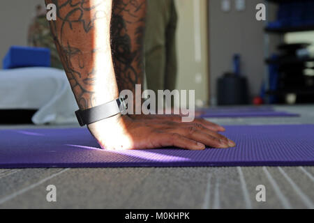 Ein Yoga Therapie Patienten bringt seine Hände auf die Matte an den unerschrockenen Geist in Fort Bragg, N.C., Dez. 14, 2017. Die Klinik konzentriert sich auf traumatische Verletzungen des Gehirns und die damit verbundenen Bedingungen und Yoga Therapie wird oft für Patienten empfohlen, die den Heilungsprozess zu erleichtern. Us-Armee Stockfoto