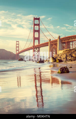 Klassische vertikale Ansicht der berühmten Golden Gate Bridge vom malerischen Baker Beach in wunderschönen goldenen Abendlicht gesehen an einem sonnigen Tag mit blauen Himmel Stockfoto
