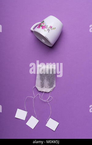 Porzellan weiße Tasse mit drei Teebeutel auf lila Hintergrund. top View Studio shot Stockfoto