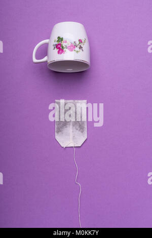Single Porzellan weiße Tasse mit einem Teebeutel auf lila Hintergrund. top View Studio shot Stockfoto