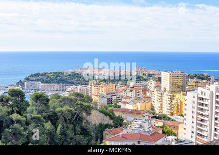 Tageslicht, Aussicht zu den hohen städtischen Gebäude, Port Hercule voll von Yachten, die Altstadt und das blaue Meer mit dem Boot auf dem Wasser verfolgen. Der strahlend blaue Himmel mit Wolken. Negati Stockfoto