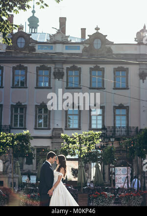 Wunderschönes romantisches portrait Der glücklich verheiratete Hände halten und zärtlich berühren Nasen auf dem Hintergrund der alten Haus mit Pflanzen bedeckt. Stockfoto