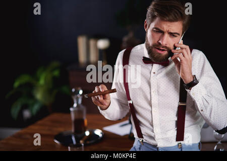 Geschäftsmann rauchen kubanische Zigarre während Business Call Stockfoto