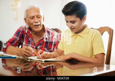 Kleiner Junge macht Schule Hausaufgaben mit alten Menschen zu Hause. Stockfoto