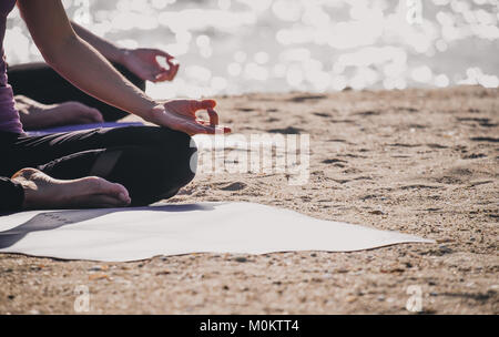 Close up Hände des Yoga Master sitzt dabei Hand Mudra und meditiert am Strand an der Küste, Ruhe und Entspannung, Wellness und gesunden Lebensstil Stockfoto