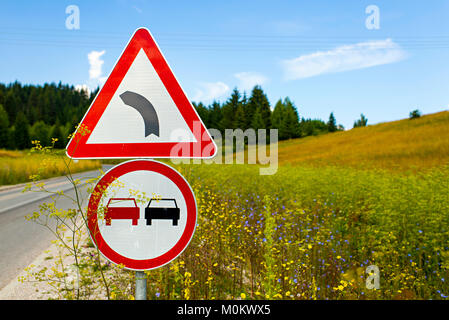 Verkehrszeichen auf einer Landstraße durch einen Berg Wiese Stockfoto