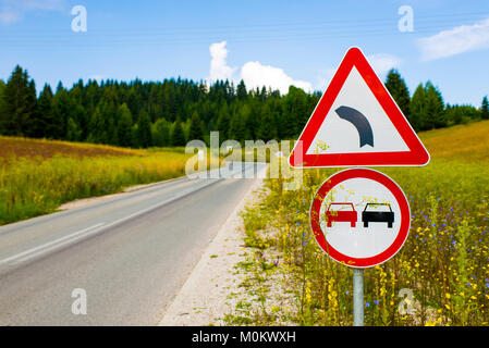 Verkehrszeichen auf einer Landstraße durch einen Berg Wiese Stockfoto