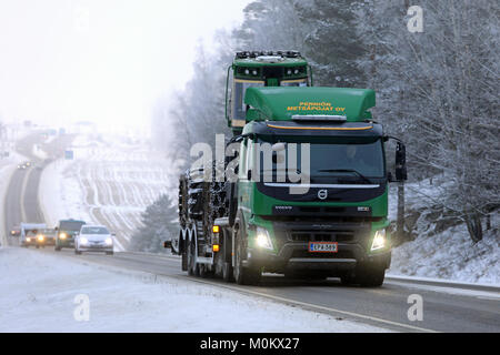SALO, FINNLAND - Januar 20, 2018: Grün Volvo FMX Lkw hols John Deere Forstmaschinen auf Anhänger entlang der Landstraße im Winter Nebel. Stockfoto