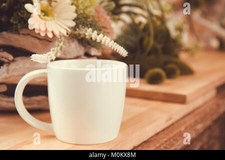 Weiß Kaffeetasse auf hölzernen Tisch im Garten des Café mit gemütlicher Atmosphäre, vintage Foto und Film Stil Stockfoto