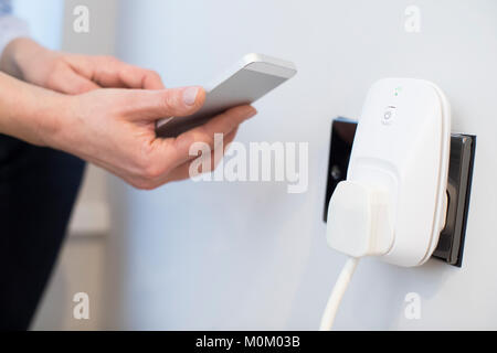 Frau Steuerung Smart Plug mit App auf Handy Stockfoto