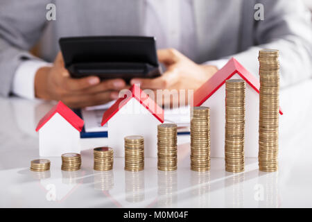 Unternehmer Berechnung Finanzierung mit Taschenrechner mit Münzen Grafik auf Schreibtisch Stockfoto