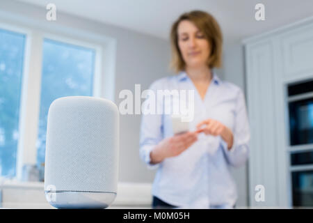 Frau Streaming Musik drahtlos vom Mobiltelefon zum Lautsprecher Stockfoto