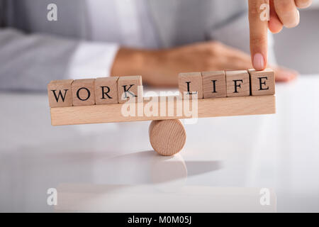 Nahaufnahme der Geschäftsmann, der mit dem Finger zeigen, Ungleichgewicht zwischen Arbeit und Leben auf hölzernen Wippe Stockfoto