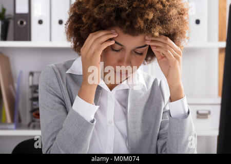 Porträt einer Afro-amerikanische Geschäftsfrau leiden unter Kopfschmerzen im Büro Stockfoto