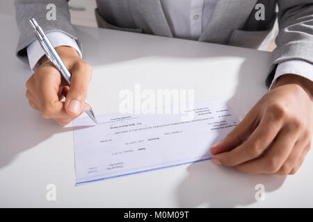 Nahaufnahme der Person Hand Unterzeichnen mit Stift am Schreibtisch überprüfen Stockfoto
