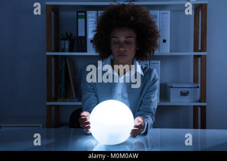 Porträt einer Afro-amerikanische Geschäftsfrau Hand auf Crystal Ball im Büro Stockfoto