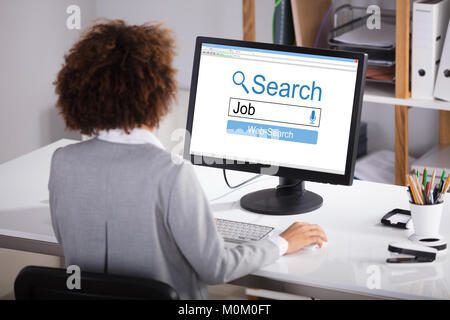 Ansicht der Rückseite eine Geschäftsfrau Suche Online Job auf dem Computer im Büro Stockfoto