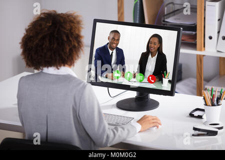 Ansicht der Rückseite eine Geschäftsfrau Videokonferenzen Kollegen auf dem Computer im Büro Stockfoto