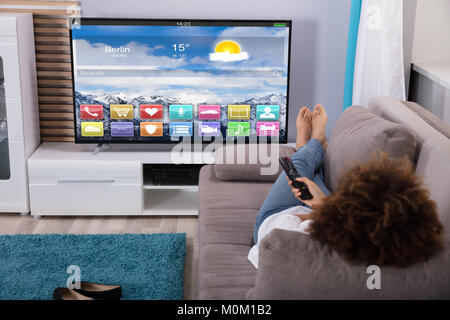 Liegende Frau auf dem Sofa Fernsehen mit bunten Anwendungen auf dem Bildschirm Stockfoto