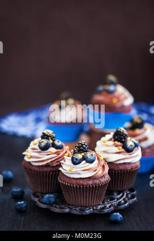 Hausgemachte leckere Schokolade Cupcakes mit frischen Beeren auf der Oberseite Stockfoto