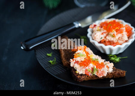 Lachs, Pastete (Rillettes) mit rotem Kaviar mit geschnittenem Brot serviert. Stockfoto