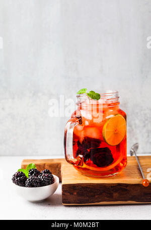 Sommer erfrischendes Getränk mit Eis und frische reife Beeren. Himbeeren und Brombeeren mit Zitrusfrüchten auf einem Stein Hintergrund Tabelle in Gläsern mit handl Stockfoto