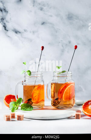 Traditionelle Eistee mit Orange und Minze und Eis in Maurergläser. Erfrischende Sommer Drink auf weißem Marmor board Stockfoto