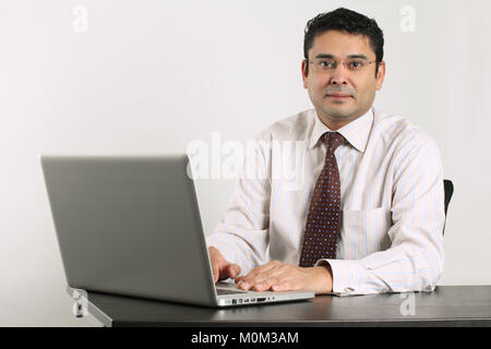 Foto von einem indischen Mann bei der Arbeit vor einem Laptop zufrieden. Stockfoto