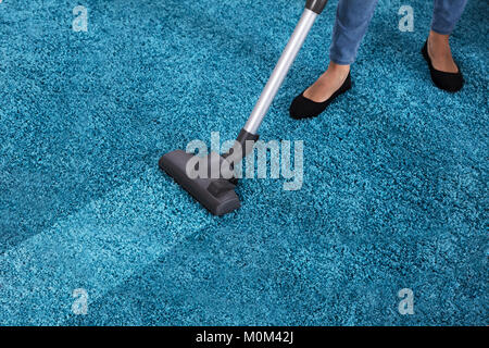 Nahaufnahme von einem Hausmeister mit Staubsauger für die Reinigung von blauen Teppich Stockfoto