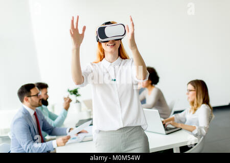 Junge Frau mit Virtual reality Simulator während der Sitzung im Büro Stockfoto